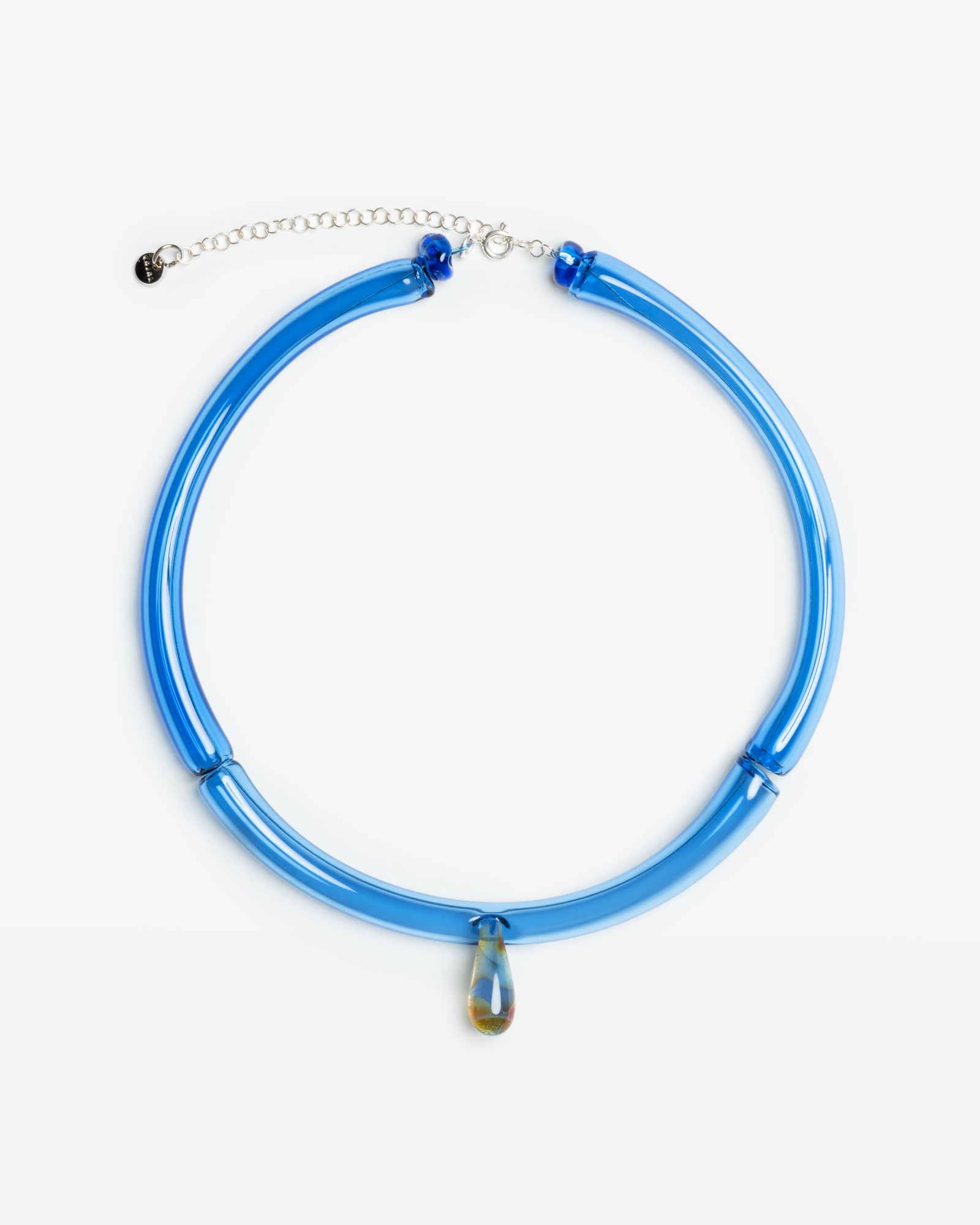 Handcrafted blue diamond necklace featuring a curved borosilicate glass design with a delicate teardrop pendant, set on an adjustable silver chain. The lightweight glass tubing creates an elegant arc in translucent light blue, showcasing Spanish artisanal glassblowing craftsmanship.