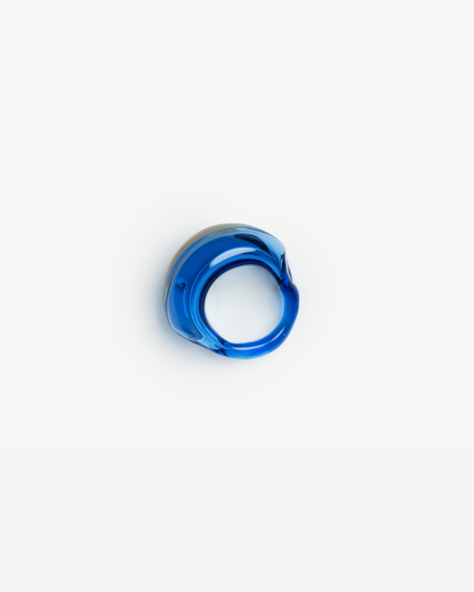 Moonlit ring handcrafted in light blue borosilicate glass, featuring a sculptural curved design against white background. Handmade in Barcelona, the transparent ring showcases organic flowing lines and minimalist aesthetic.